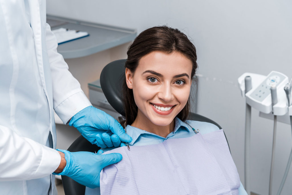 Patiente avec un dentiste sourit après son traitement de dentisterie générale.